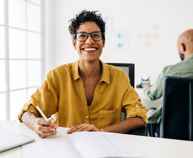 A woman sitting at a desk smiling.