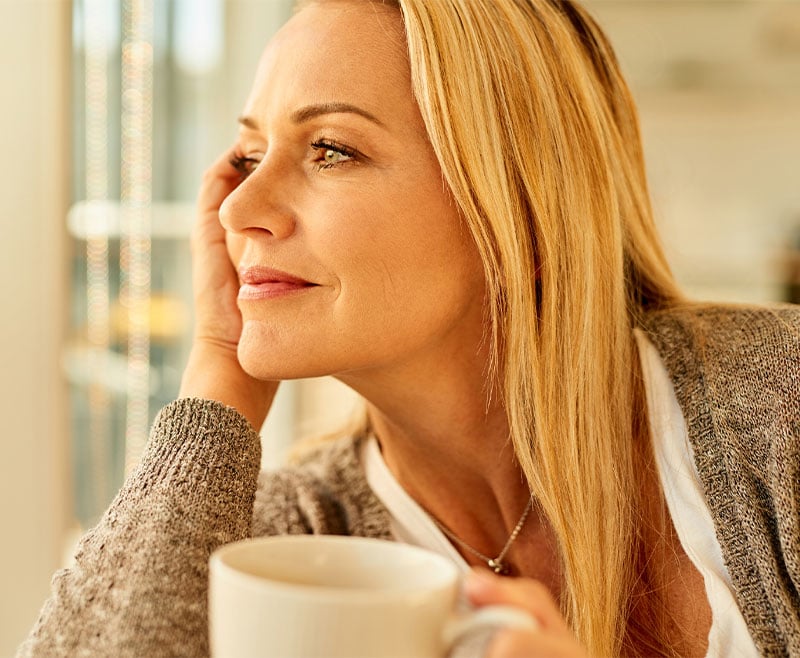 A woman sitting calmly with coffee thinking.